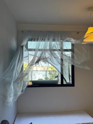 a window with a white curtain in a room at Swita Nir - Hot tub, Beach & Barbeque in Ashdod