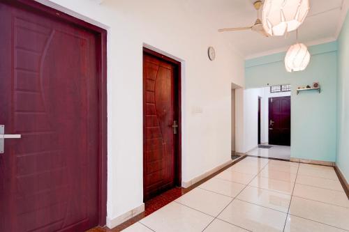 a hallway with two red doors and a tile floor at Super Hotel O Palarivattom Metro Station Formerly South Gate in Edappally