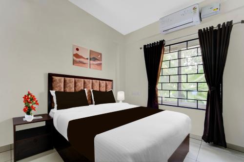 a bedroom with a large bed and a window at Super Collection O Valiyavila Junction Formerly Prism Heights in Trivandrum