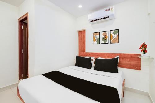 Un dormitorio con una cama blanca con almohadas negras. en Super Hotel O Neredmet Road, en Hyderabad