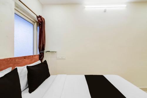 Un dormitorio con una cama con almohadas blancas y negras. en Super Hotel O Neredmet Road, en Hyderabad