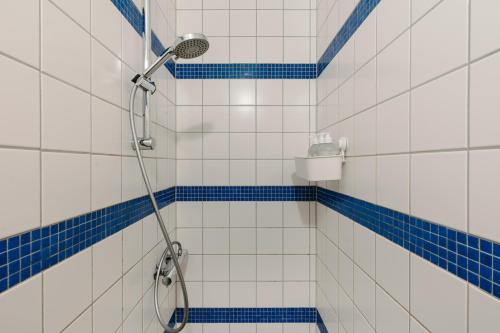 a shower in a bathroom with blue and white tiles at Hotel Kriunes in Reykjavík