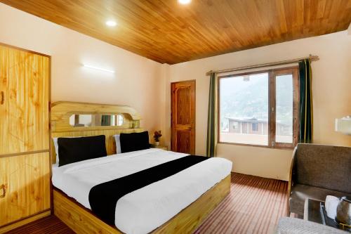 a bedroom with a large bed and a window at Hotel O Aleo Near Mall Road Formerly Aman Cottage in Manāli