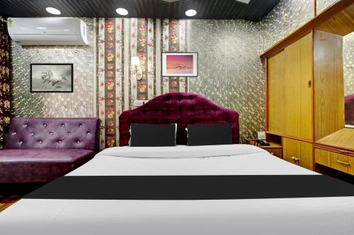 a bedroom with a bed and two purple chairs at Hotel O Residency Road Srinagar in Srinagar