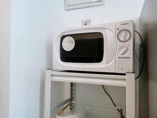 a microwave sitting on a shelf in a room at Fanhua Life IN Nanjing West Road Store 2 in Shanghai