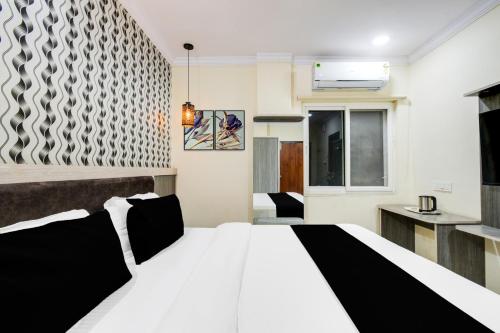 a bedroom with a black and white bed and a kitchen at Super Townhouse Shamshabad Paradise Formerly Blue Petals Hotel in Shamshabad