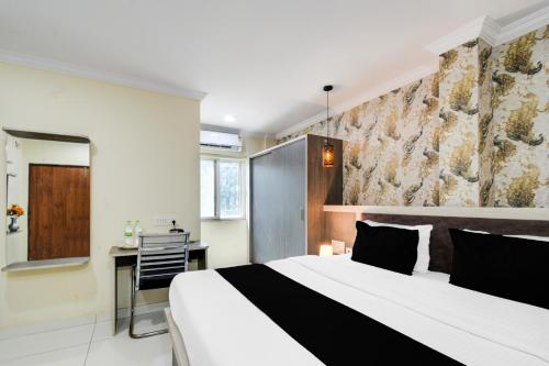 a bedroom with a large white bed and a desk at Super Townhouse Shamshabad Paradise Formerly Blue Petals Hotel in Shamshabad