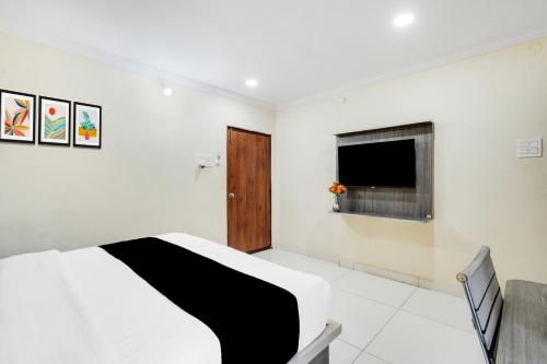 a bedroom with a bed and a flat screen tv at Super Townhouse Shamshabad Paradise Formerly Blue Petals Hotel in Shamshabad