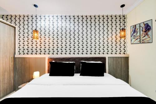 a bedroom with a large white bed with black pillows at Super Townhouse Shamshabad Paradise Formerly Blue Petals Hotel in Shamshabad