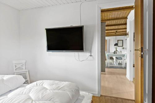 a white bedroom with a flat screen tv on a wall at BL1136-Blokhus-Graevlingevej-6 in Blokhus