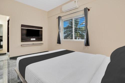 a white bedroom with a bed and a window at Super Collection O Peenya 2nd stage Formerly the JK Grand in Bengaluru