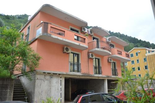 un edificio rosa con coches estacionados frente a él en Lero Apartments, en Budva