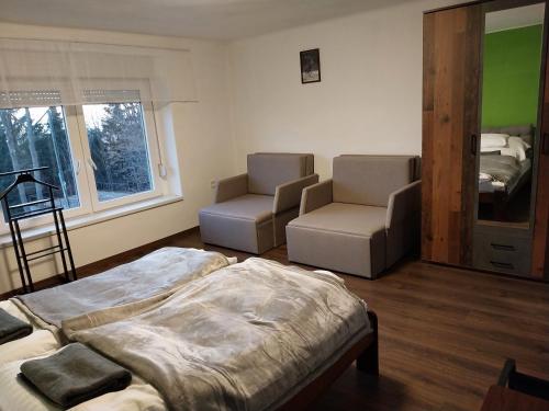 a room with two beds and two chairs in it at Mátrai5Vendégház Galyatető in Mátraszentimre