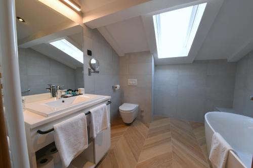 a bathroom with a sink and a toilet and a skylight at Aparthotel Milenij in Baška Voda