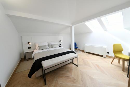 a white bedroom with a bed and a yellow chair at Aparthotel Milenij in Baška Voda