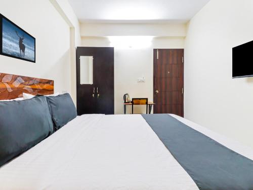 a bedroom with a large white bed and a tv at Super Townhouse Bellandur Near Embassy Tech Village in Bengaluru