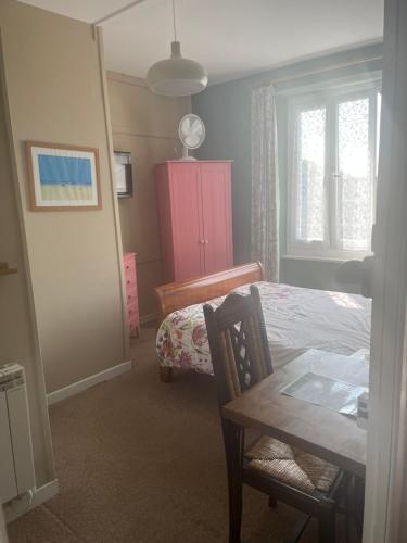 a bedroom with a bed and a table and a pink cabinet at Webb's of Glomel in Glomel