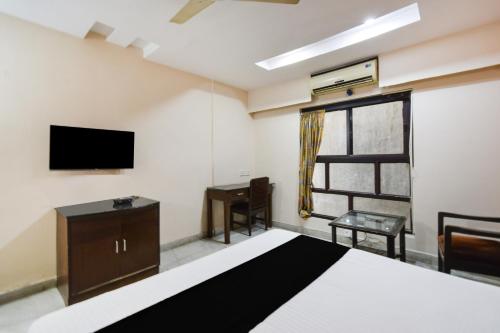 a bedroom with a bed and a tv and a window at Townhouse OAK Secunderabad Near Railway Station Formerly Hotel Brahma in Hyderabad