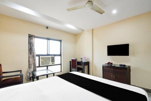 a bedroom with a bed and a tv and a window at Townhouse OAK Secunderabad Near Railway Station Formerly Hotel Brahma in Hyderabad