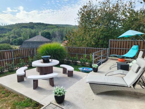 a patio with a table and chairs and an umbrella at Panoráma Vendégház Jásd in Jásd