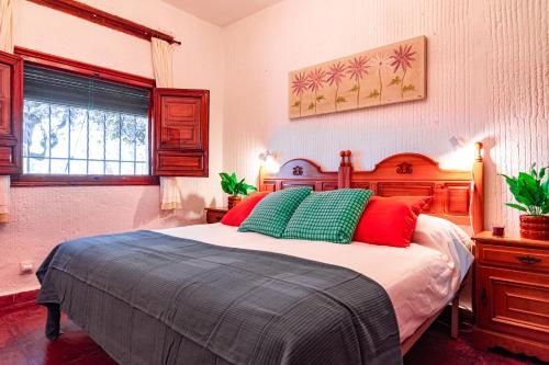 a bedroom with a bed with green and red pillows at Edomus Castillo de las Guardas in Seville