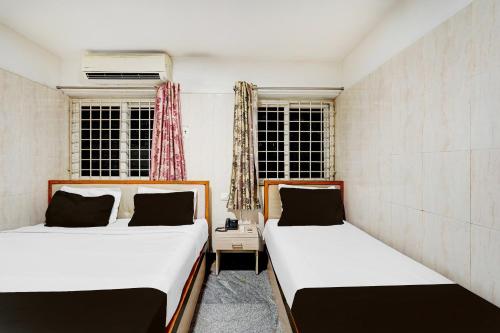 two beds in a small room with two windows at Super Hotel O Porur Formerly Jeya's Elite in Chennai