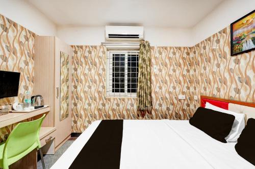 a bedroom with a bed and a desk and a window at Super Hotel O Porur Formerly Jeya's Elite in Chennai