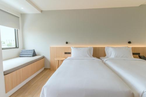 a bedroom with two beds and a window at PAAK Hotel Suvarnabhumi in Lat Krabang