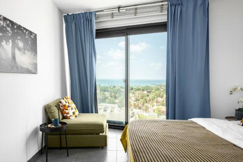 a bedroom with a bed and a chair and a large window at Boutique Duplex 3BR Florentin in Mashabbe Sade