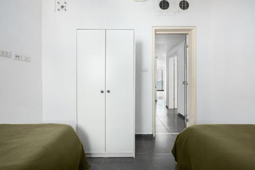 a bedroom with two beds and a white closet at Boutique Duplex 3BR Florentin in Mashabbe Sade