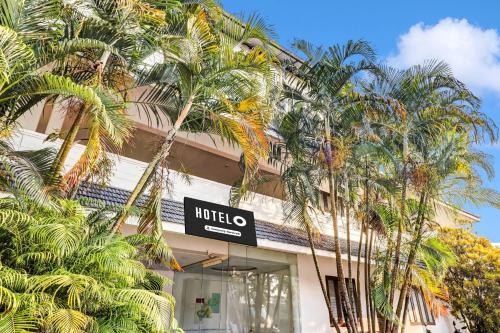 a hotel with palm trees in front of a building at Hotel O Kazhakoottam Near AL SAJ Convention Centre in Trivandrum