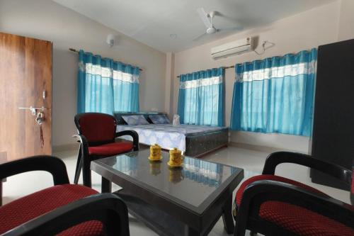 Una sala de estar con una cama, una mesa y sillas. en Banobitan Resort, en Lataguri