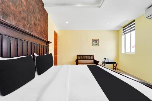 a room with a bed with black and white pillows at Super Townhouse Ernakulam North in Ernakulam