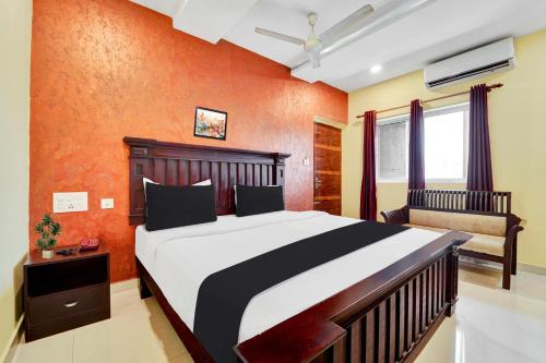 a bedroom with a large bed with an orange wall at Super Townhouse Ernakulam North in Ernakulam