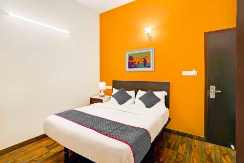 a bedroom with a bed with an orange wall at Super Collection O Singasandra Hosa Road in Bengaluru
