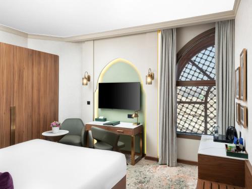 a hotel room with a bed and a desk and a tv at Elaf Taiba Hotel in Al Madinah