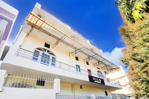 a white building with balconies and a blue sky at Super Hotel O Sudhowala Near Nanda ki Chowk in Dehradun