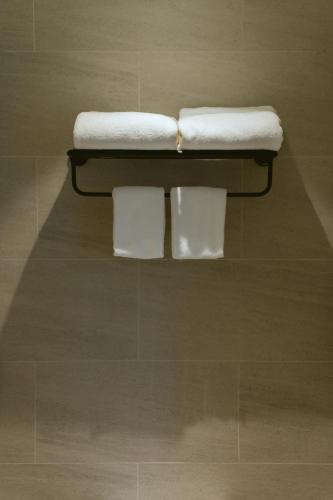 two towels are sitting on a shelf in a bathroom at PAAK Hotel Suvarnabhumi in Lat Krabang