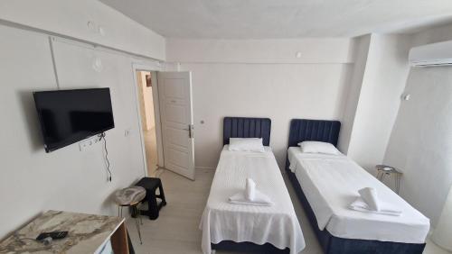 a room with two beds and a flat screen tv at Mery Inn in Pamukkale