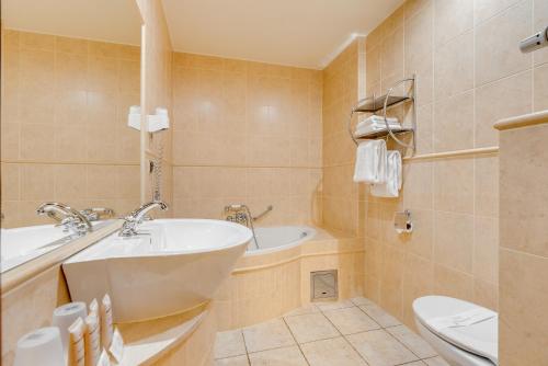 a bathroom with a tub and a sink and a toilet at Hotel Diament Bella Notte Katowice - Chorzów in Chorzów