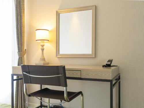 a desk with a chair and a mirror and a lamp at Kumamoto Hotel Castle in Kumamoto