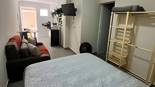 a room with a bed and a couch and a shelf at Studio kitnet Apartamento Privativo Jundiai 03 in Jundiaí