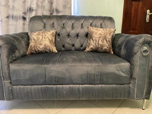 a black leather couch with two pillows on it at Nansana residence in Kampala