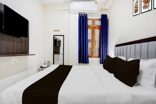 a bedroom with a large white bed with blue curtains at Super Collection O Nagwa Lanka Varanasi in Varanasi