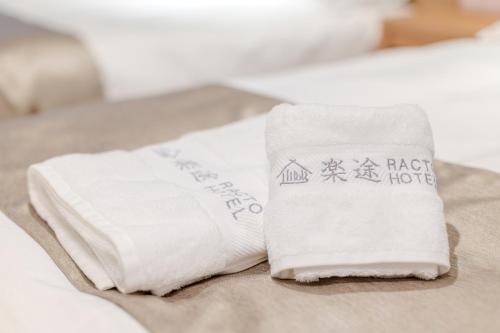 two white towels sitting on top of a bed at 楽途ホテル 東十条 in Tokyo