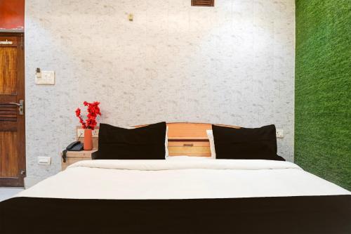 a bedroom with a bed with white sheets and black pillows at Super Collection O Kanpur Central Railway Junction Formerly Maharaja Palace in Kānpur