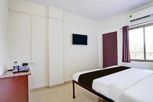 a white bedroom with a bed and a window at Super Hotel O Rane Nagar formerly Shree Mangal Complex in Nashik