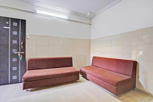 a waiting room with two red seats in a room at Super Hotel O Rane Nagar formerly Shree Mangal Complex in Nashik