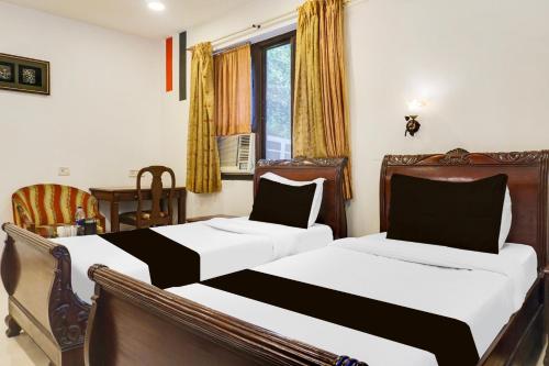 a bedroom with two beds and a window at Super Townhouse Oak Prabhat Road in Pune