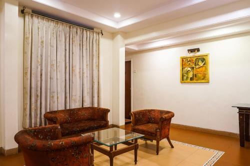a living room with two chairs and a glass table at Super Townhouse Oak Prabhat Road in Pune